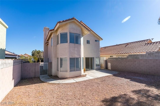 back of property with a tile roof, stucco siding, a fenced backyard, a patio, and a gate