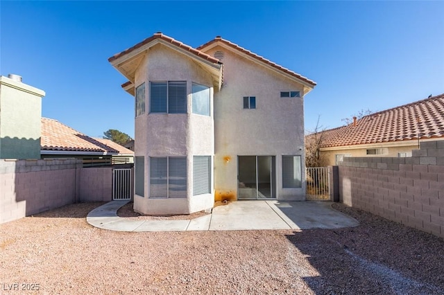 rear view of house featuring a patio area, a gate, a fenced backyard, and stucco siding