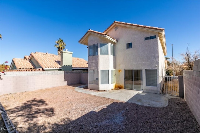 back of property with a tiled roof, a patio area, a fenced backyard, and stucco siding