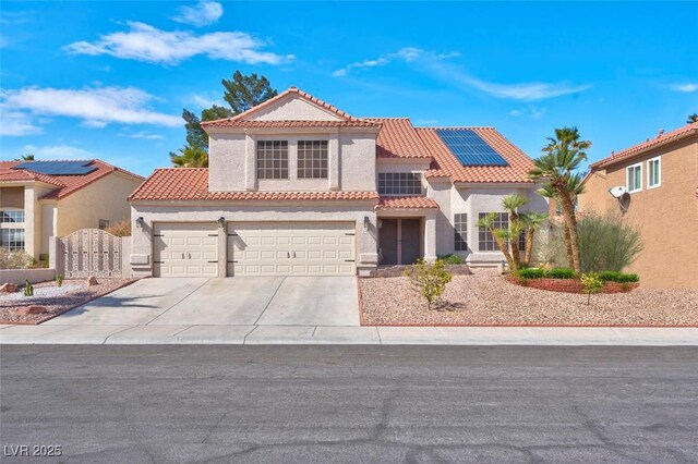 mediterranean / spanish house featuring a gate, driveway, a tiled roof, stucco siding, and solar panels