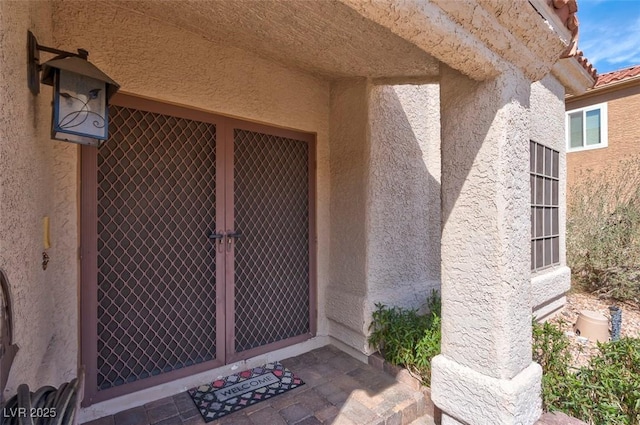 view of exterior entry with stucco siding and a tile roof