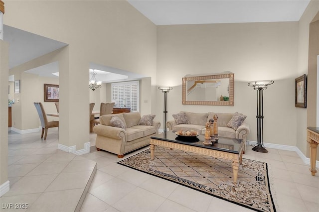 living room with a high ceiling, light tile patterned floors, baseboards, and a chandelier