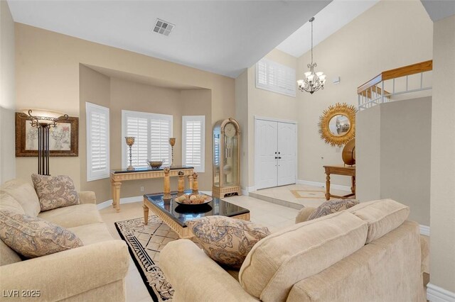 living room with light tile patterned flooring, an inviting chandelier, baseboards, a high ceiling, and visible vents