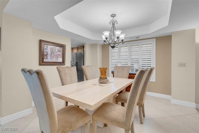 dining space with light tile patterned floors, a notable chandelier, a raised ceiling, and baseboards