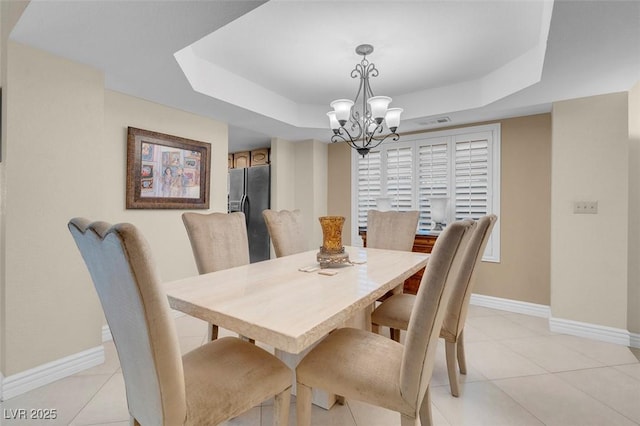 dining area with baseboards, light tile patterned flooring, a tray ceiling, and a chandelier