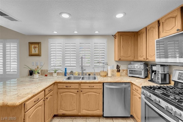 kitchen featuring visible vents, light tile patterned floors, appliances with stainless steel finishes, a peninsula, and a sink