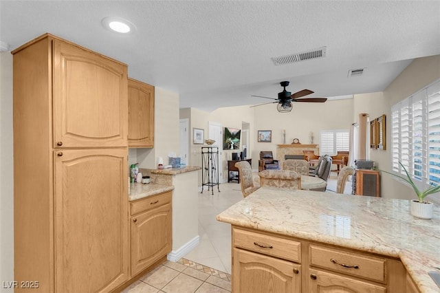 kitchen featuring visible vents, a ceiling fan, light tile patterned flooring, and a fireplace