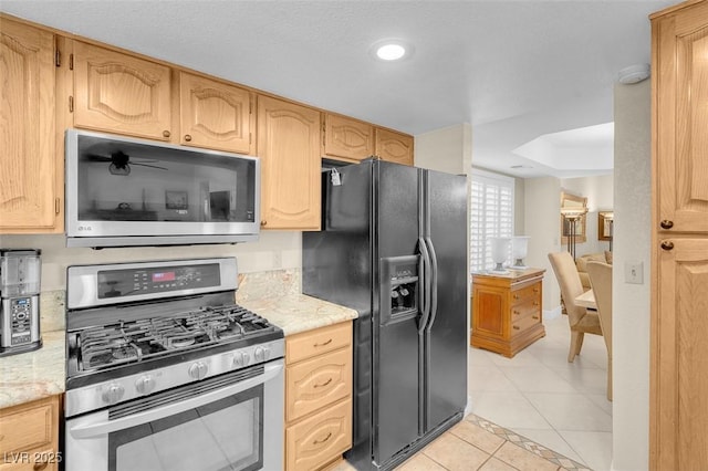 kitchen with light tile patterned floors, stainless steel appliances, light stone countertops, and light brown cabinetry