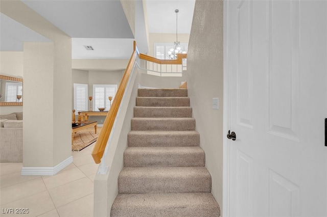 staircase with an inviting chandelier, tile patterned floors, baseboards, and visible vents