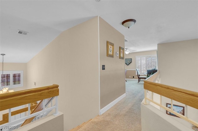 hall with visible vents, an upstairs landing, baseboards, carpet flooring, and lofted ceiling