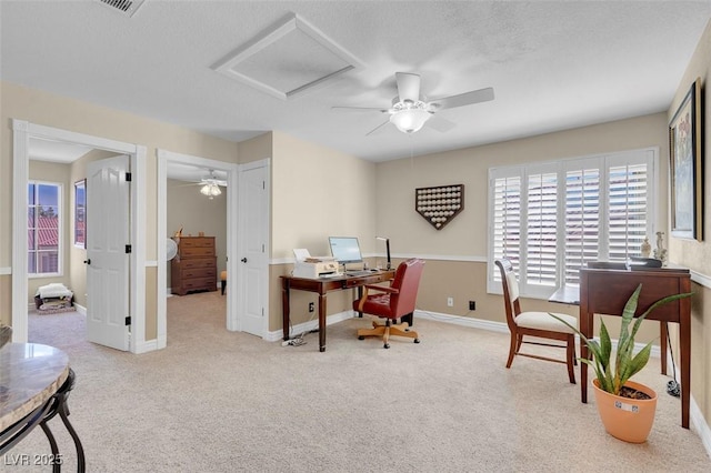 carpeted office space with attic access, baseboards, and ceiling fan