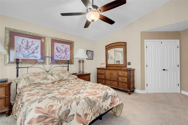 carpeted bedroom featuring a closet, lofted ceiling, baseboards, and a ceiling fan