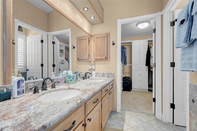 full bathroom featuring double vanity, a spacious closet, tile patterned floors, and a sink