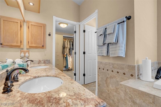 bathroom featuring double vanity, a walk in closet, and a sink