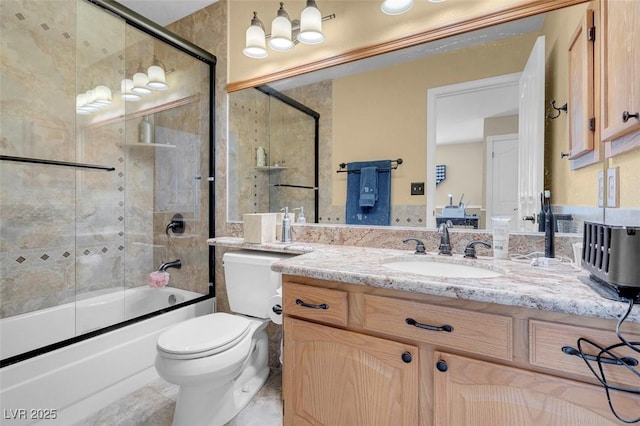 full bath featuring toilet, vanity, and shower / bath combination with glass door