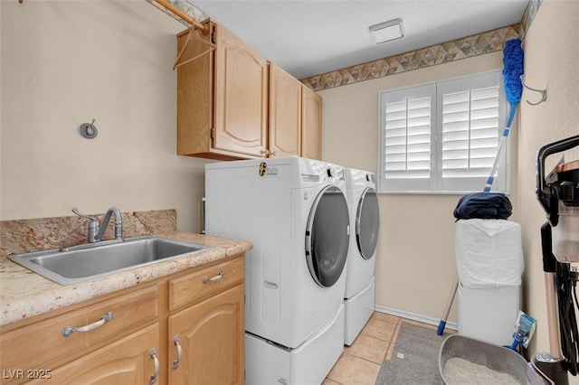 washroom featuring a sink, light tile patterned flooring, washing machine and clothes dryer, baseboards, and cabinet space