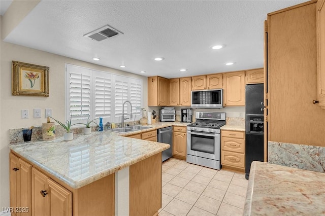 kitchen with stainless steel appliances, a peninsula, a sink, recessed lighting, and light brown cabinets