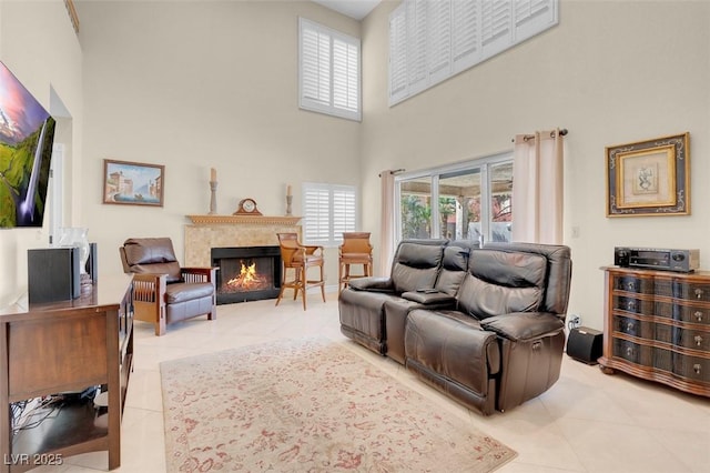 living area featuring light tile patterned flooring, a fireplace, and a towering ceiling