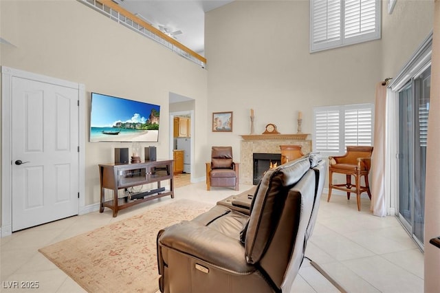 living area with light tile patterned floors, baseboards, a towering ceiling, and a fireplace