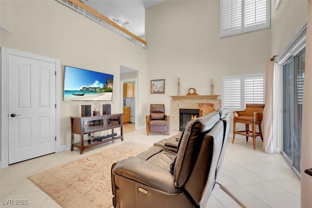 living area featuring a high end fireplace, a towering ceiling, baseboards, and light tile patterned floors