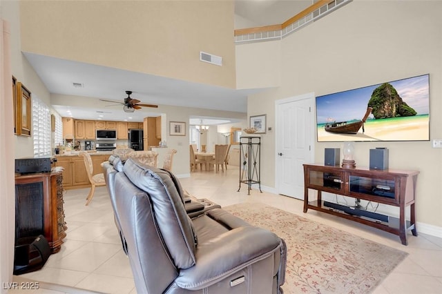 living room featuring a ceiling fan, light tile patterned flooring, a towering ceiling, and visible vents