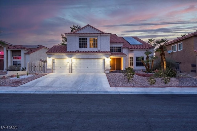 view of front of home featuring driveway, a tiled roof, a garage, stucco siding, and solar panels