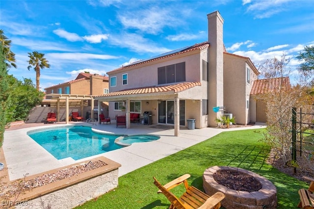 back of house with stucco siding, a pool with connected hot tub, a tile roof, a fire pit, and a patio area