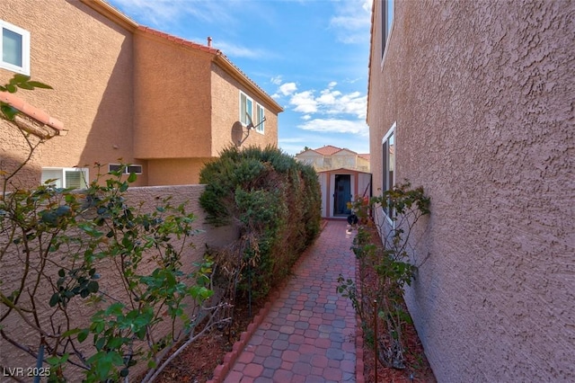 view of property exterior with fence, an outdoor structure, a storage shed, and stucco siding