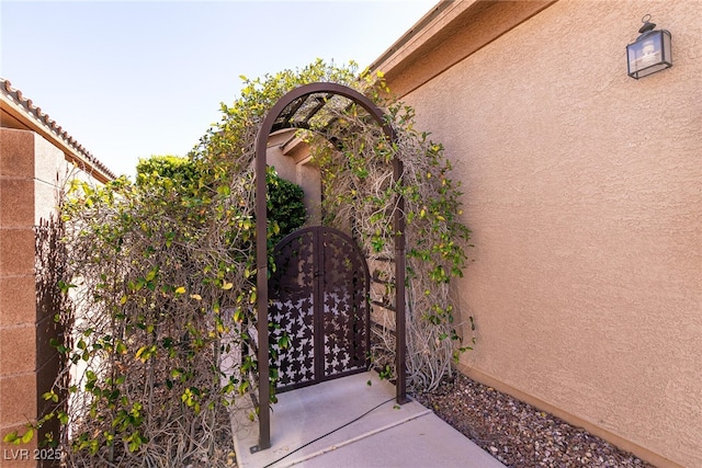 view of exterior entry featuring stucco siding, fence, and a gate