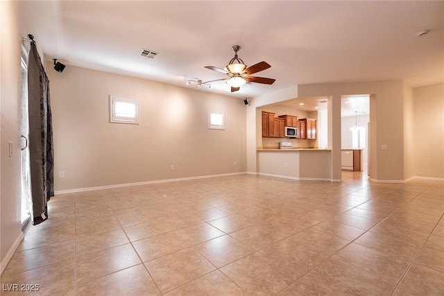 unfurnished living room with light tile patterned floors, visible vents, baseboards, and ceiling fan