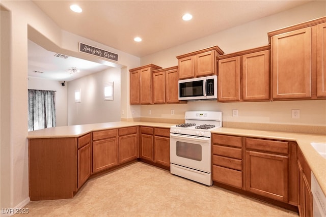 kitchen with white appliances, light countertops, and a peninsula