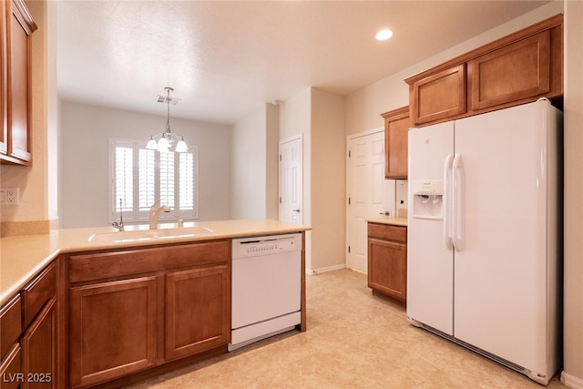 kitchen with a sink, white appliances, brown cabinetry, and light countertops