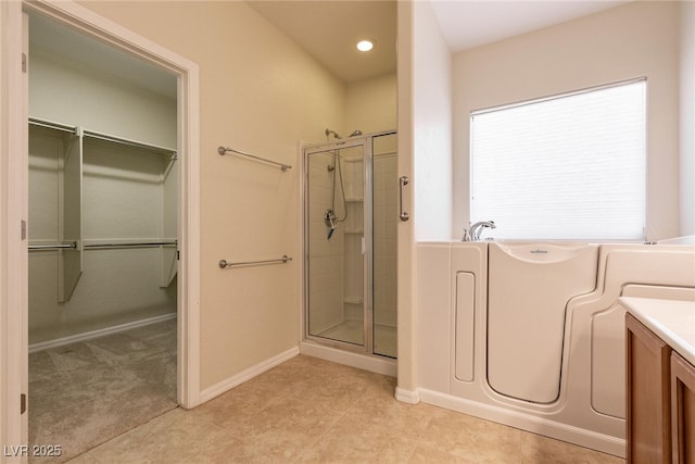 bathroom with vanity, a shower stall, a spacious closet, tile patterned floors, and a bath