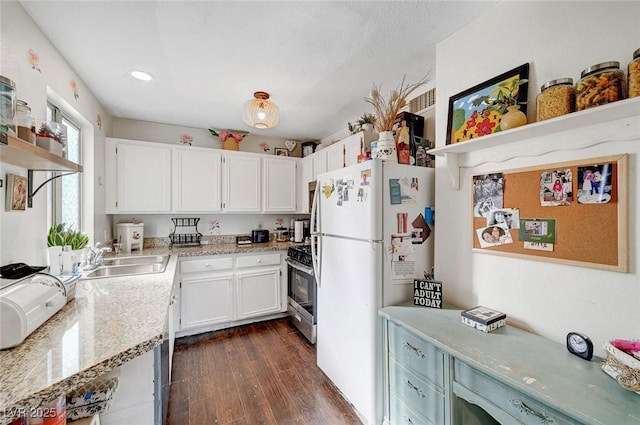 kitchen with open shelves, freestanding refrigerator, a sink, dark wood-type flooring, and stainless steel gas range oven