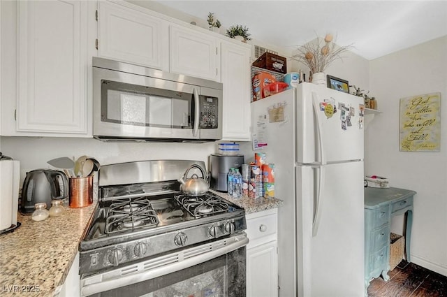 kitchen featuring appliances with stainless steel finishes, white cabinetry, dark wood-type flooring, and baseboards