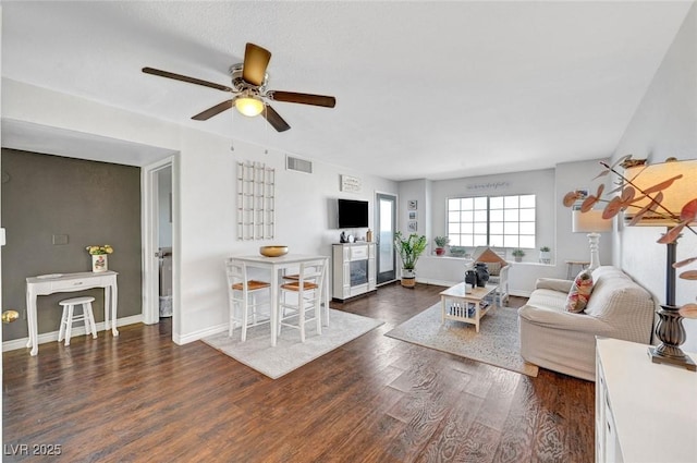 living area featuring wood finished floors, visible vents, baseboards, ceiling fan, and wine cooler