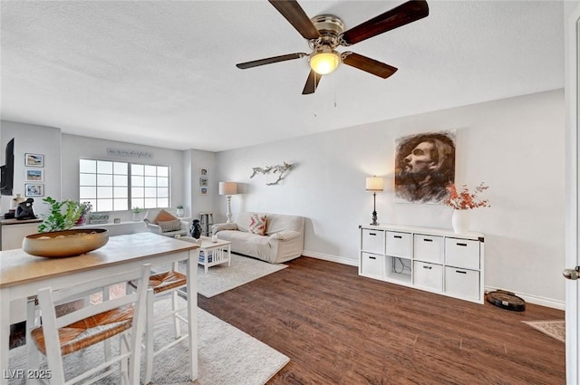 living area featuring baseboards, dark wood-type flooring, ceiling fan, and a textured ceiling