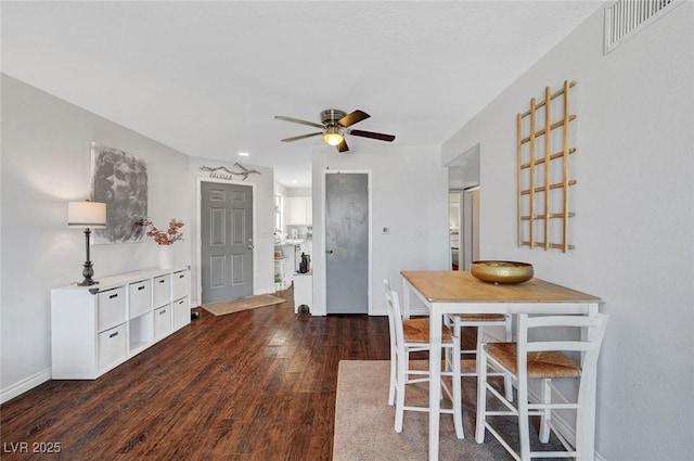 dining room featuring dark wood-style floors, visible vents, baseboards, and a ceiling fan