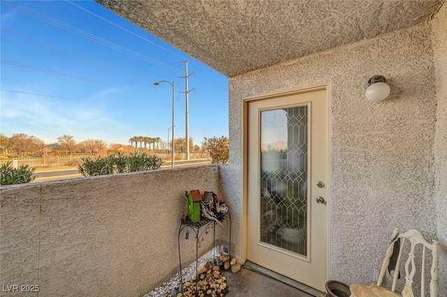 property entrance with a balcony and stucco siding