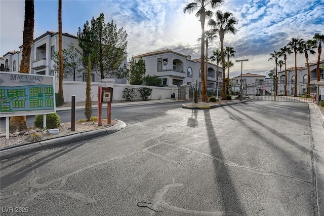 view of street with curbs, a residential view, a gated entry, and a gate