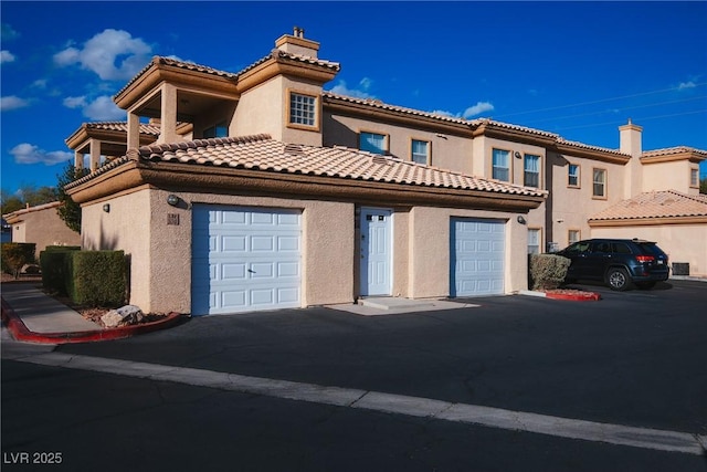 mediterranean / spanish-style house featuring stucco siding, a chimney, and a tile roof