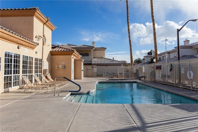 pool with a patio area and fence