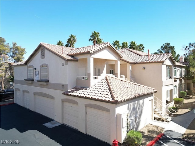 mediterranean / spanish-style home with stucco siding, an attached garage, driveway, and a tile roof