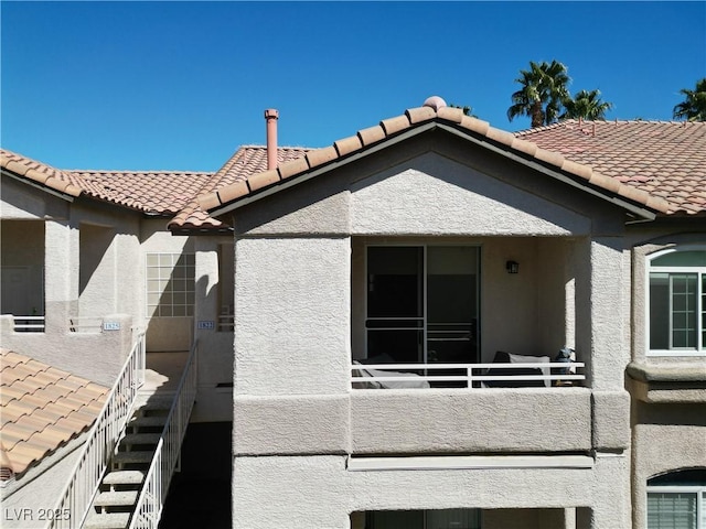 back of house with a tiled roof and stucco siding