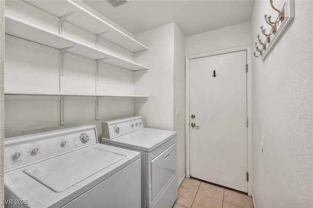 laundry area featuring washer and dryer, laundry area, light tile patterned floors, and visible vents