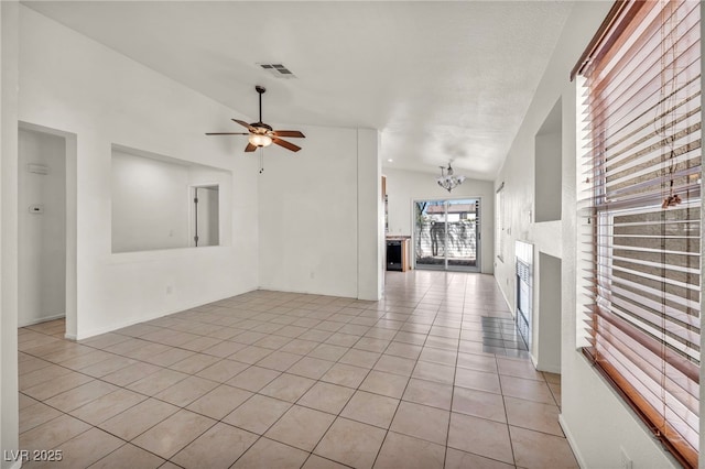 spare room featuring vaulted ceiling, light tile patterned floors, ceiling fan with notable chandelier, and visible vents