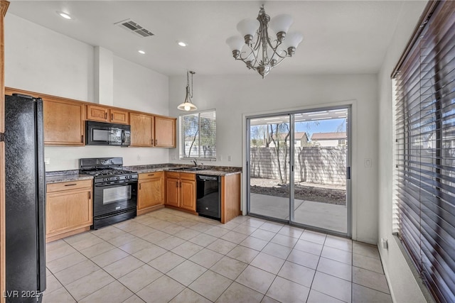 kitchen with visible vents, pendant lighting, dark stone countertops, black appliances, and a sink