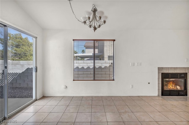 unfurnished dining area featuring an inviting chandelier, light tile patterned floors, and a tile fireplace