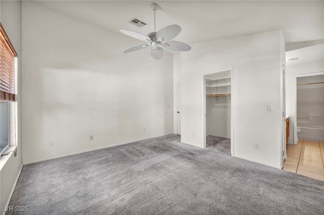 unfurnished bedroom featuring a spacious closet, visible vents, light colored carpet, high vaulted ceiling, and a ceiling fan