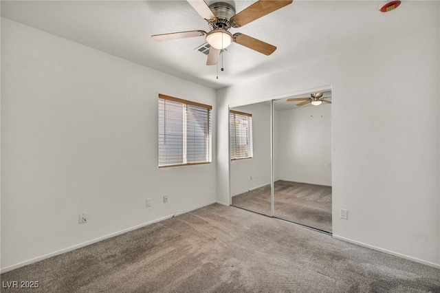 unfurnished bedroom featuring visible vents, carpet, a closet, and a ceiling fan